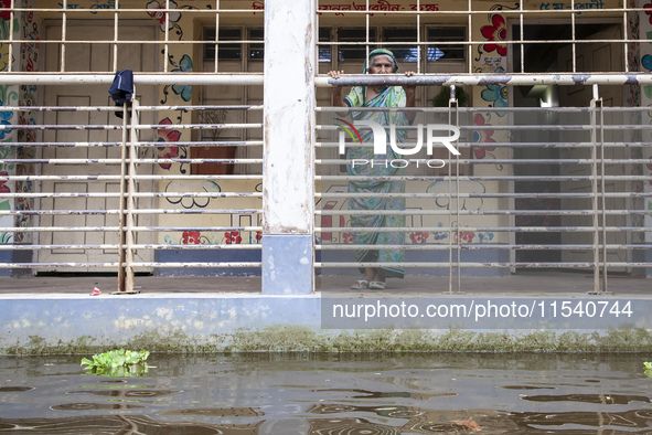 An elderly woman stands on the balcony looking out at the floodwaters of a flood shelter in Sonapur Union, Sonaimuri Upazila, Noakhali Distr...