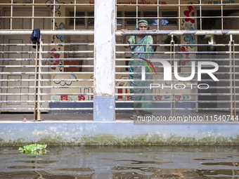 An elderly woman stands on the balcony looking out at the floodwaters of a flood shelter in Sonapur Union, Sonaimuri Upazila, Noakhali Distr...