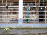 An elderly woman stands on the balcony looking out at the floodwaters of a flood shelter in Sonapur Union, Sonaimuri Upazila, Noakhali Distr...