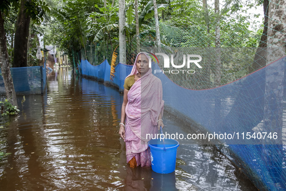 An elderly woman stands in knee-deep flood water in Sonapur Union of Sonaimuri Upazila of Noakhali District of Chittagong Division in Noakha...