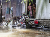 A woman washes essential items in floodwaters in front of her house in Sonapur Union of Sonaimuri Upazila of Noakhali District of Chittagong...