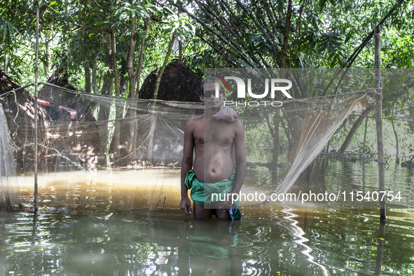 A man stands in knee-deep flood water in a village from Sonapur Union of Sonaimuri Upazila, Noakhali District, Chittagong Division, Banglade...