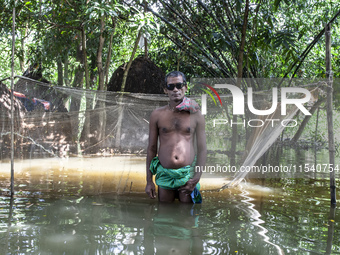 A man stands in knee-deep flood water in a village from Sonapur Union of Sonaimuri Upazila, Noakhali District, Chittagong Division, Banglade...