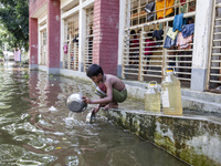 A child washes dishes in flood water in front of a shelter in Sonapur Union, Sonaimuri Upazila, Noakhali District, Chittagong Division, Bang...