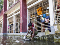 A child washes dishes in flood water in front of a shelter in Sonapur Union, Sonaimuri Upazila, Noakhali District, Chittagong Division, Bang...