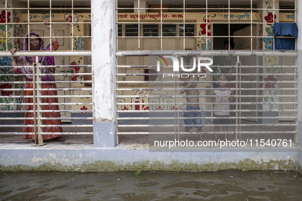 People stand on the balcony after taking shelter in a school due to floods in Sonapur Union of Sonaimuri Upazila of Noakhali District of Chi...