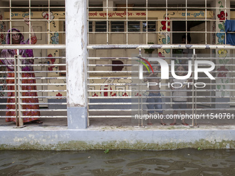 People stand on the balcony after taking shelter in a school due to floods in Sonapur Union of Sonaimuri Upazila of Noakhali District of Chi...