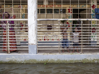 People stand on the balcony after taking shelter in a school due to floods in Sonapur Union of Sonaimuri Upazila of Noakhali District of Chi...