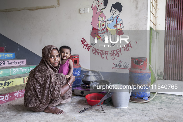 A woman cooks rice with a gas stove at a flood shelter in Sonapur Union, Sonaimuri Upazila, Noakhali District, Chittagong Division, Banglade...