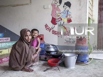 A woman cooks rice with a gas stove at a flood shelter in Sonapur Union, Sonaimuri Upazila, Noakhali District, Chittagong Division, Banglade...