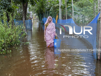 An elderly woman stands in knee-deep flood water in Sonapur Union of Sonaimuri Upazila of Noakhali District of Chittagong Division in Noakha...