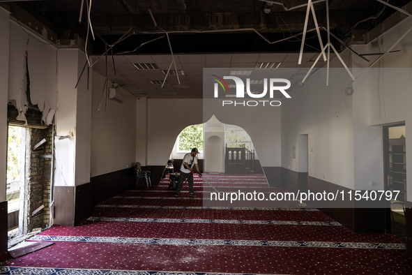 Believers and volunteers clean up the building of the Islamic Cultural Center and Mosque, which is damaged after the Russian missile attacks...