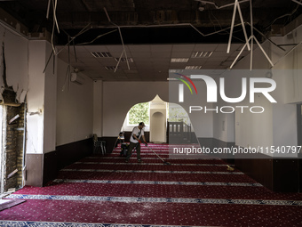 Believers and volunteers clean up the building of the Islamic Cultural Center and Mosque, which is damaged after the Russian missile attacks...