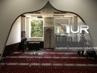 Believers and volunteers clean up the building of the Islamic Cultural Center and Mosque, which is damaged after the Russian missile attacks...