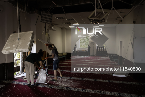 Believers and volunteers clean up the building of the Islamic Cultural Center and Mosque, which is damaged after the Russian missile attacks...