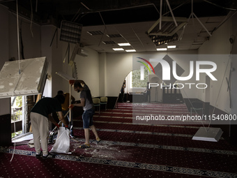 Believers and volunteers clean up the building of the Islamic Cultural Center and Mosque, which is damaged after the Russian missile attacks...