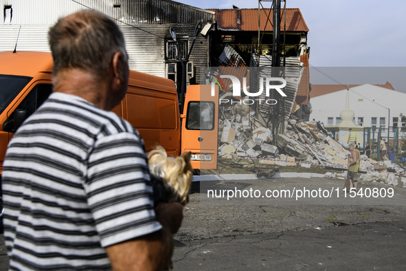 People stand near the sports complex of a university, a heavily damaged and partially collapsed building, after the Russian missile attacks...