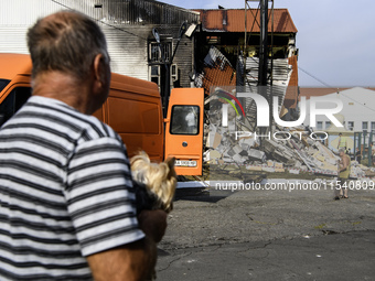 People stand near the sports complex of a university, a heavily damaged and partially collapsed building, after the Russian missile attacks...