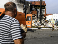 People stand near the sports complex of a university, a heavily damaged and partially collapsed building, after the Russian missile attacks...