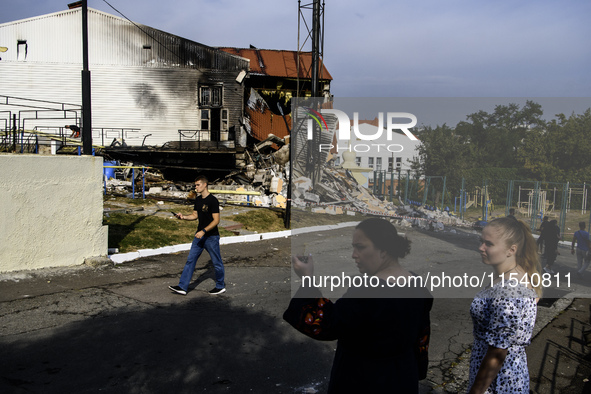 People stand near the sports complex of a university, a heavily damaged and partially collapsed building, after the Russian missile attacks...