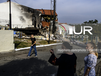 People stand near the sports complex of a university, a heavily damaged and partially collapsed building, after the Russian missile attacks...