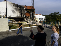 People stand near the sports complex of a university, a heavily damaged and partially collapsed building, after the Russian missile attacks...