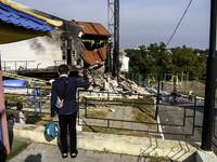 A schoolboy who comes to celebrate the beginning of the educational year stands near the sports complex of a university, a heavily damaged a...