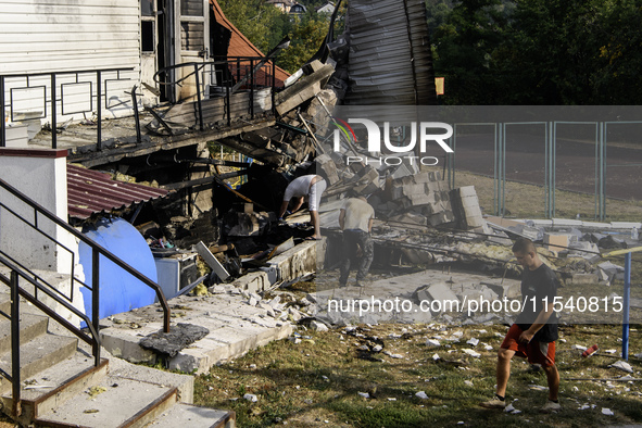 People work near the sports complex of a university with a heavily damaged and partially collapsed building after the Russian missile attack...