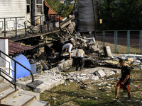 People work near the sports complex of a university with a heavily damaged and partially collapsed building after the Russian missile attack...