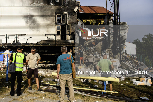 People stand near the sports complex of a university, a heavily damaged and partially collapsed building, after the Russian missile attacks...