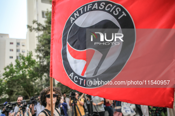 A young female demonstrator waves an Anti-Fascist Action flag as others shout slogans during a demonstration staged by human rights activist...