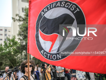 A young female demonstrator waves an Anti-Fascist Action flag as others shout slogans during a demonstration staged by human rights activist...