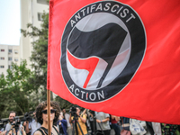 A young female demonstrator waves an Anti-Fascist Action flag as others shout slogans during a demonstration staged by human rights activist...