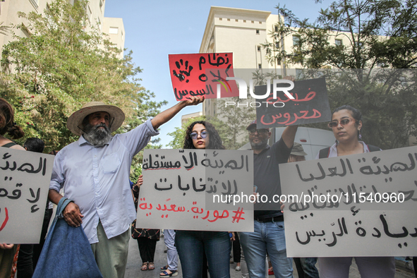 A young female demonstrator holds a placard that reads in Arabic, ''The non-independent High Authority for Elections, fake elections of Kais...