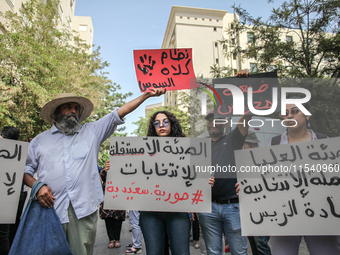 A young female demonstrator holds a placard that reads in Arabic, ''The non-independent High Authority for Elections, fake elections of Kais...