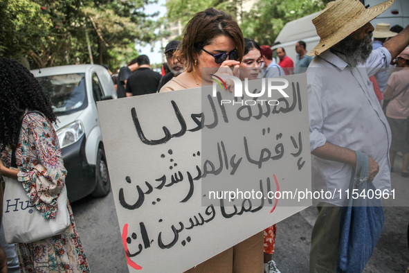 A female demonstrator holds a placard that reads in Arabic, ''the High Authority For eliminating the competing candidates,'' during a demons...