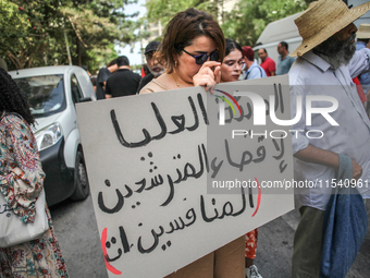 A female demonstrator holds a placard that reads in Arabic, ''the High Authority For eliminating the competing candidates,'' during a demons...