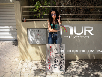 A young demonstrator smokes a cigarette next to a placard that reads in Arabic, ''the non-independent High Authority for Elections, fake ele...