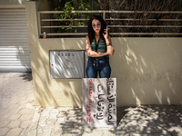 A young demonstrator smokes a cigarette next to a placard that reads in Arabic, ''the non-independent High Authority for Elections, fake ele...