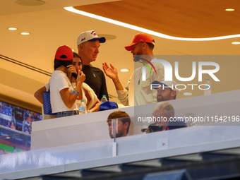 NBA star Stephen Curry stands in the owner's box chatting with former NBA star Chris Mullin during the baseball game against the Boston Red...