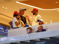 NBA star Stephen Curry stands in the owner's box chatting with former NBA star Chris Mullin during the baseball game against the Boston Red...