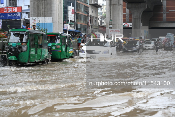 Vehicles and rickshaws attempt to navigate the waterlogged streets of Dhaka with passengers on September 3, 2024, after heavy monsoon rains...