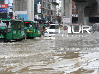 Vehicles and rickshaws attempt to navigate the waterlogged streets of Dhaka with passengers on September 3, 2024, after heavy monsoon rains...