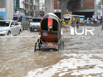 Vehicles and rickshaws attempt to navigate the waterlogged streets of Dhaka with passengers on September 3, 2024, after heavy monsoon rains...