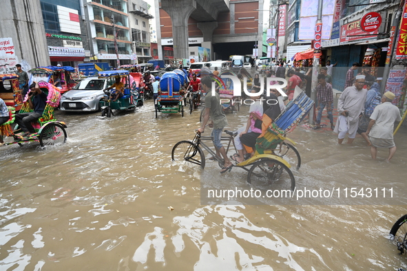 Vehicles and rickshaws attempt to navigate the waterlogged streets of Dhaka with passengers on September 3, 2024, after heavy monsoon rains...