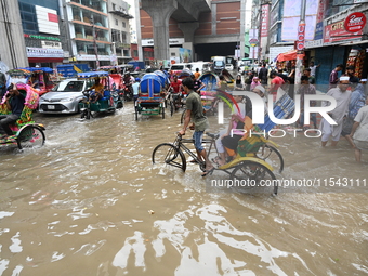 Vehicles and rickshaws attempt to navigate the waterlogged streets of Dhaka with passengers on September 3, 2024, after heavy monsoon rains...