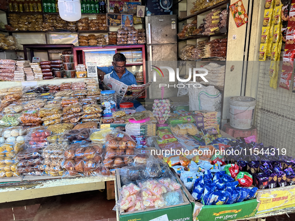 A shopkeeper reads a newspaper at the Connemara market (Palayam Market) in Thiruvananthapuram, Kerala, India, on April 13, 2024. The Connema...