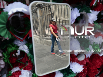 A woman reflects in a mirror in the Zocalo of Mexico City, Mexico, on September 3, 2024, on the eve of the Grito de Independencia of Mexico...