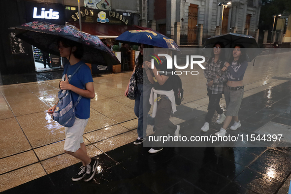 Passersby walk in the rain on Madero Avenue in Mexico City, Mexico, on September 3, 2024, on the eve of Mexican Independence Day on Septembe...