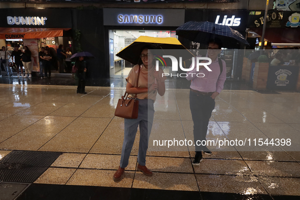 Passersby walk in the rain on Madero Avenue in Mexico City, Mexico, on September 3, 2024, on the eve of Mexican Independence Day on Septembe...